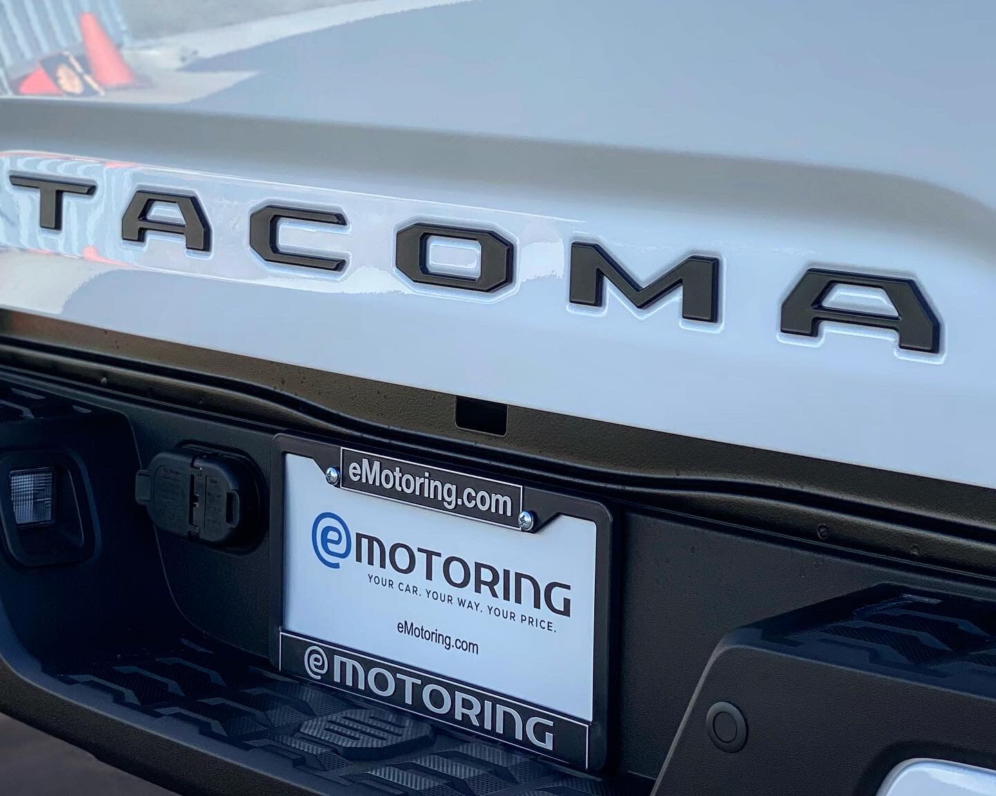 A white Toyota Tacoma with an eMotoring plate frame