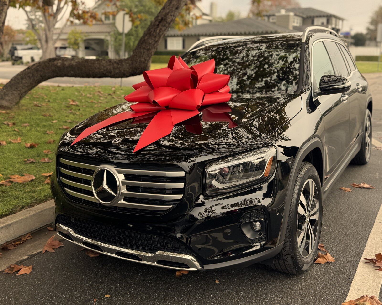 A black Mercedes-Benz GLB delivered with a red bow and eMotoring plate